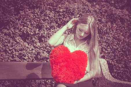 心胸大红的失望女人爱和感情坐在长椅上心胸大红的伤痕累女人背景图片