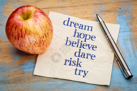 梦想希望相信敢冒险和尝试笔迹在餐巾纸上与新鲜苹果背景图片