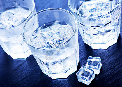 喝冷水玻璃中冰雪立方体的冷水背景