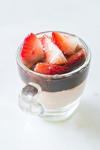 巧克力Mousse沾满了白底玻璃杯中的草莓果高清图片