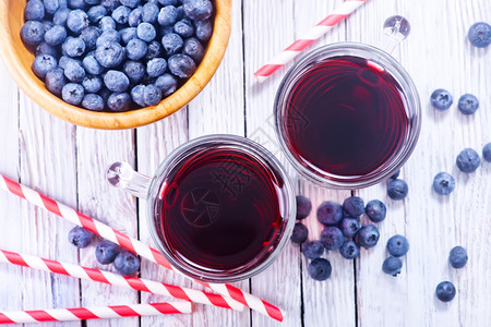 蓝莓果汁在玻璃和桌子上高清图片