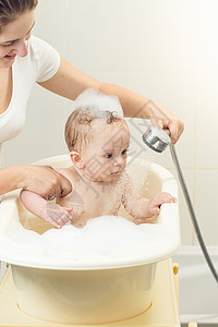可爱小男孩在洗澡时用淋浴头的肖像卫生高清图片素材