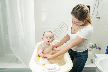 年轻母亲在洗澡时帮她儿子图片