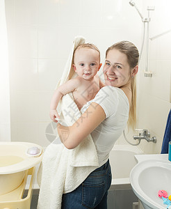 微笑的母亲在洗完澡后用毛巾覆盖婴儿的肖像幸福高清图片素材