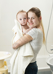 快乐的年轻母亲洗澡后抱着婴儿的肖像女性的高清图片素材