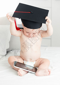聪明婴儿概念毕业时可爱的男孩子在数码平板电脑上浏览互联网图片