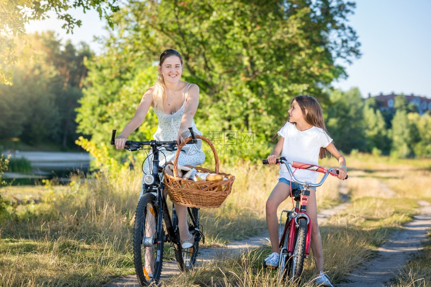 美丽的年轻母亲和女儿骑着自行车去野餐图片