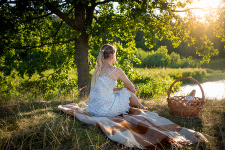 美寂寞女人的陶形象在大树下放松看着日落毯子高清图片素材