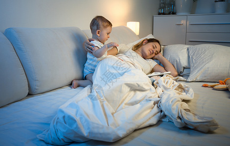 厌倦的母亲在婴儿唤醒她时试图睡觉图片
