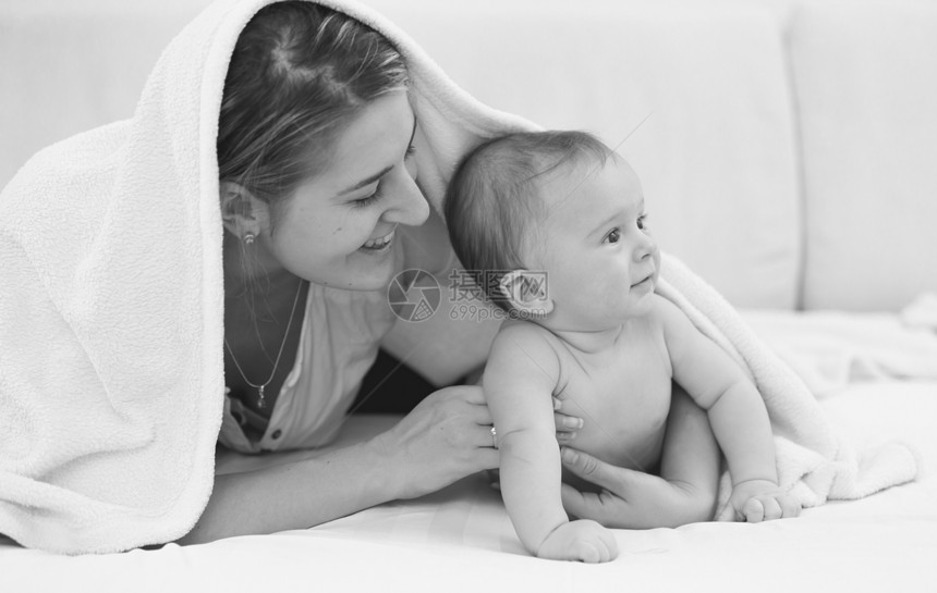 带着6个月的儿子躺在床上年轻快乐母亲黑白像图片