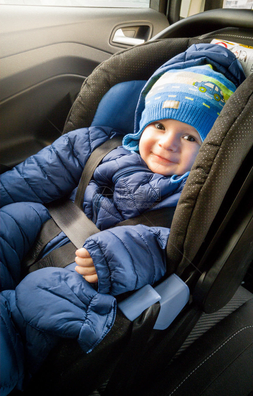 坐在汽车儿童座椅上戴着帽子的可爱笑男孩图片