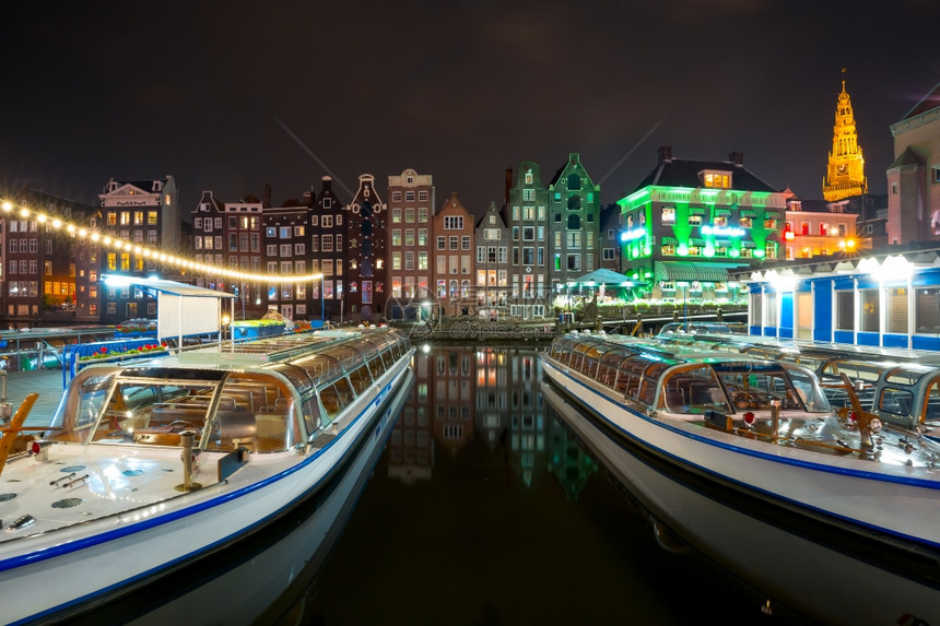 美丽的典型荷兰舞厅OudeKerk教堂和在荷兰的阿姆斯特丹运河Damrak的旅游船图片