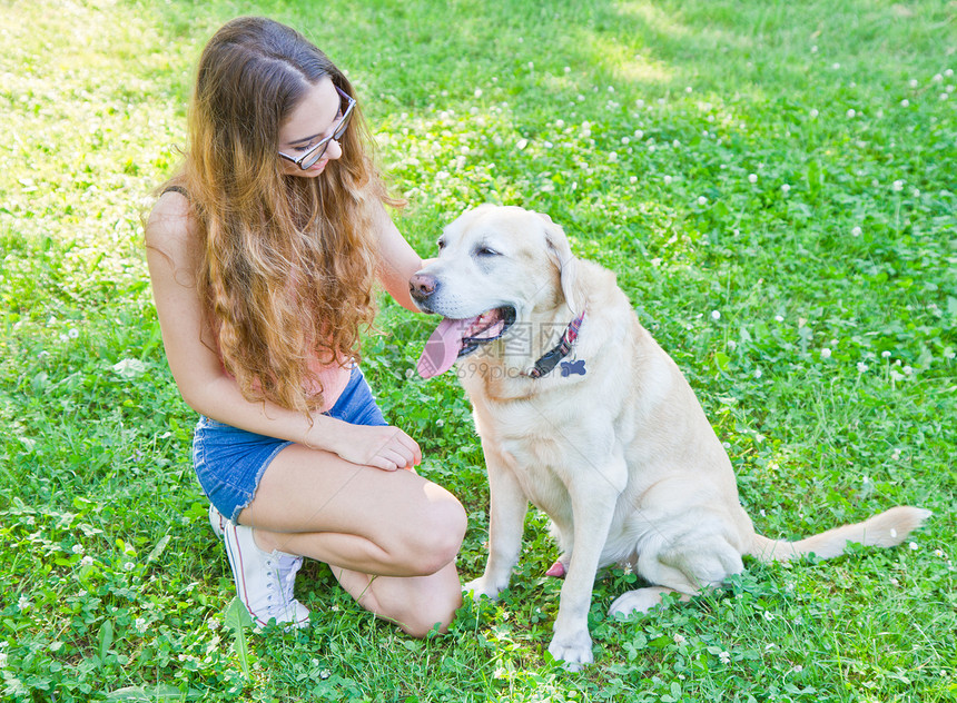 女孩在公园里玩她的拉布多猎犬图片