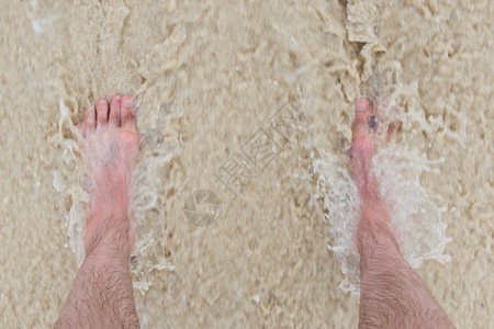 快速浪涌进来脚站立在沙滩上图片