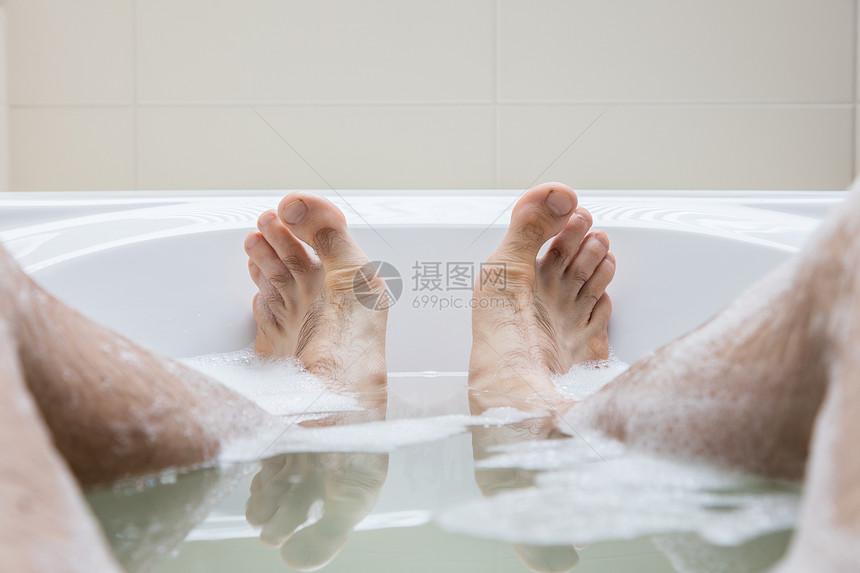 男人脚在明亮的白浴缸里有选择地关注脚趾图片
