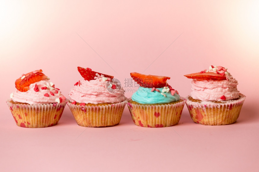 彩色纸杯蛋糕的剪贴照片上面有喷洒和鲜草莓以粉红背景排成一图片