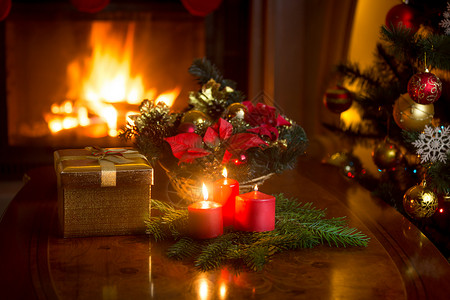 美丽的圣诞花圈在客厅用红蜡烛和燃烧的壁炉图片