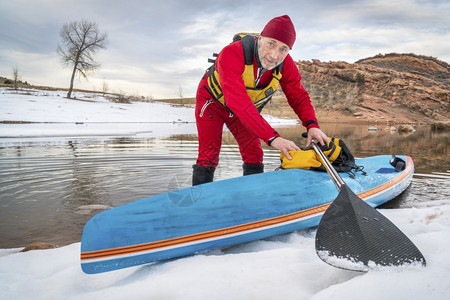 穿着干衣的高级男护和一个赛车手在科罗拉多湖边的站起桨板冬季风景图片