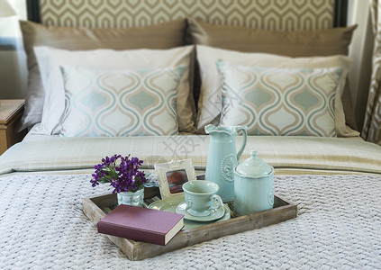 酒店杯子装饰盘托配有书籍茶叶和床上花朵背景