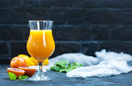 新鲜橙子和果汁在桌上的玻璃杯中图片