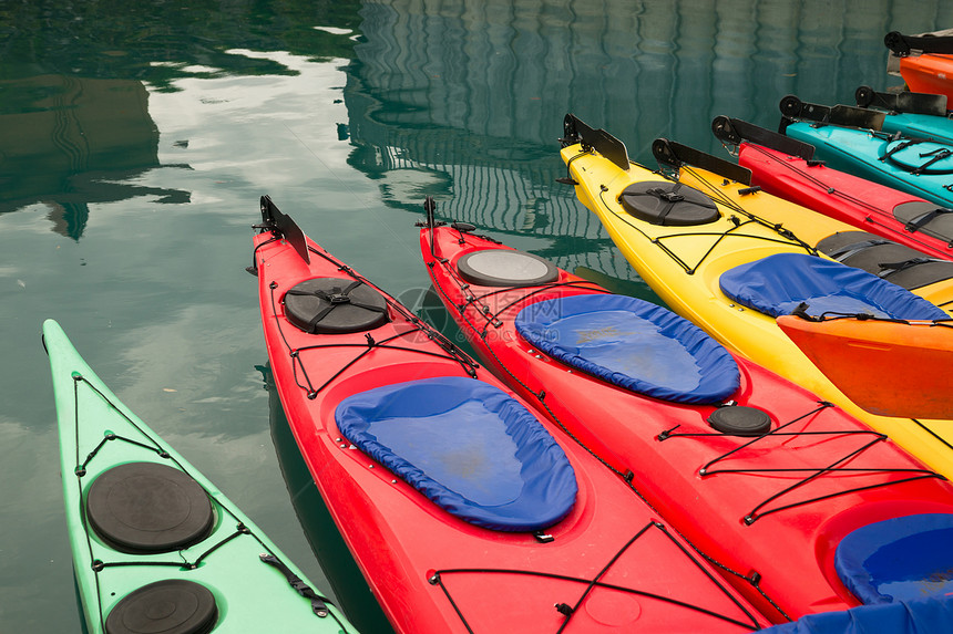 红色Teal黄茶和橙色Kayaks漂浮在彩色水上图片