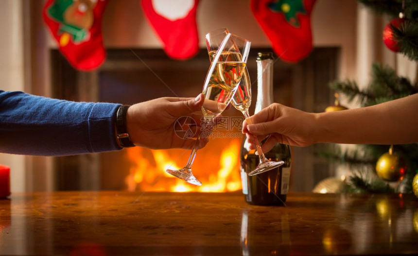 男人和女一起吃圣诞晚餐和紧贴着玻璃杯的火炉边图片