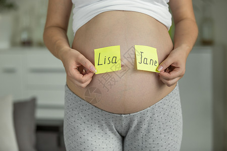 肚子上选择婴儿名字的孕妇母亲高清图片素材