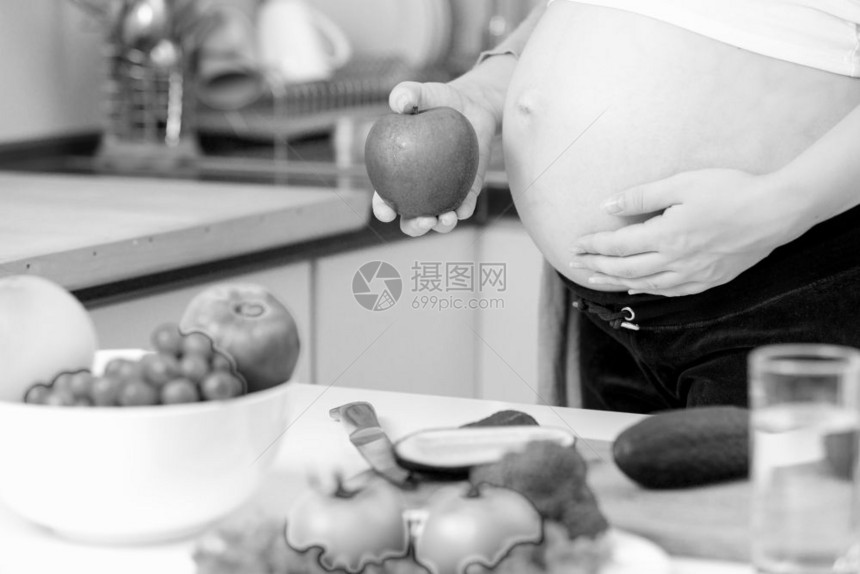 在厨房装上绿苹果的孕妇黑白照片图片