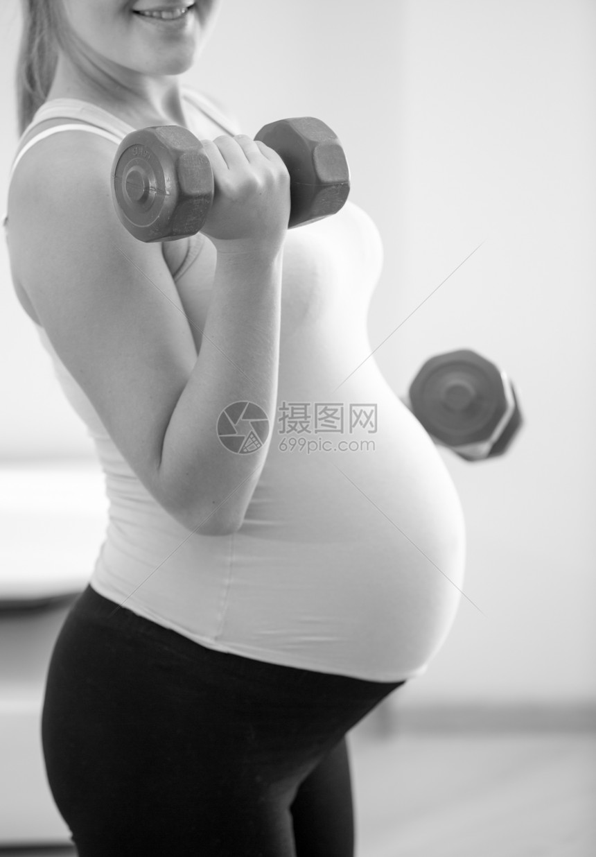 孕妇举起哑铃的黑白近身照片图片