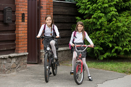 两个穿着校服的快乐女孩骑自行车上学图片