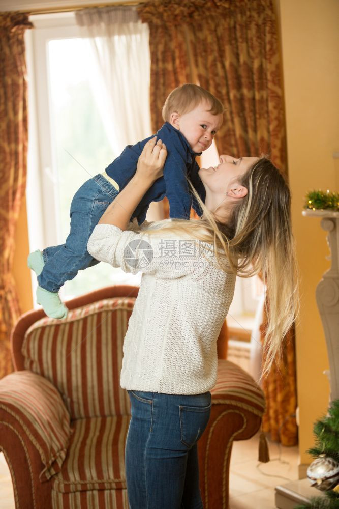母亲抱着10个月大的儿子和装饰圣诞树图片
