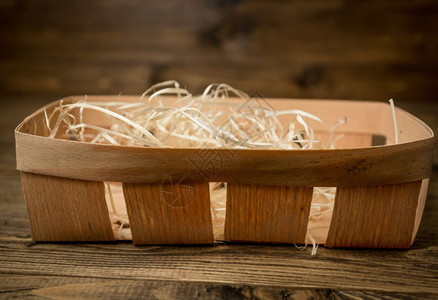 空的小篮子稻草覆盖躺在旧木制桌子上木材高清图片素材