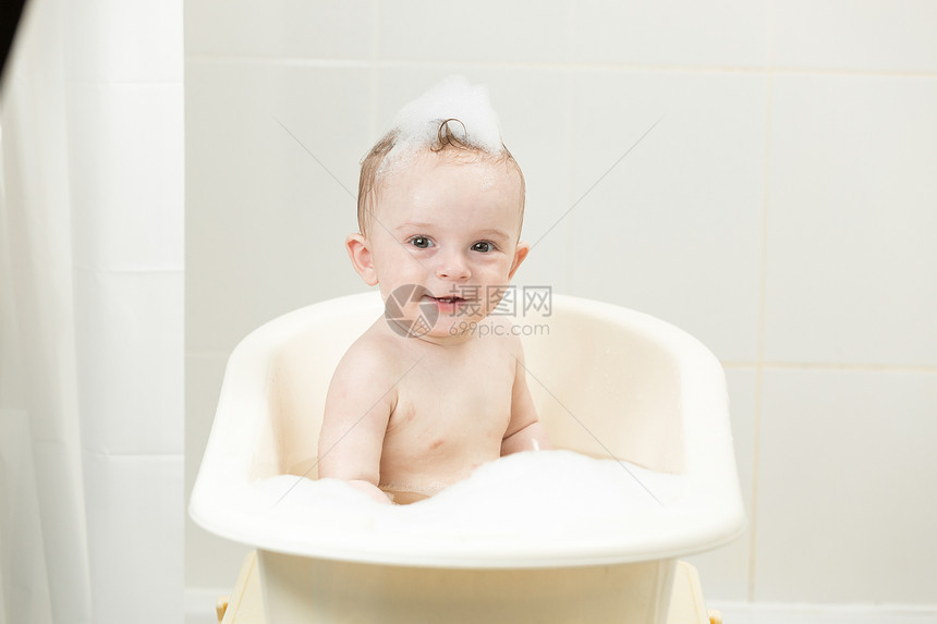 坐在浴缸里沾满泡沫的笑的男孩图片