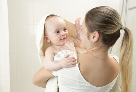 洗完澡后微笑的母亲用毛巾把婴儿包在上童年高清图片素材