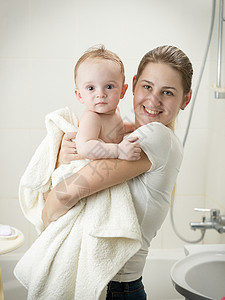 年轻母亲洗完澡后在浴室亲婴儿幸福的高清图片素材