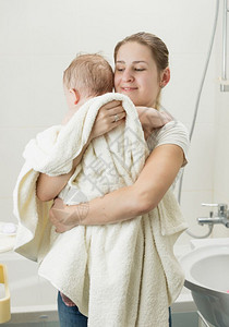 快乐的年轻母亲在洗完澡后抱着婴儿图片