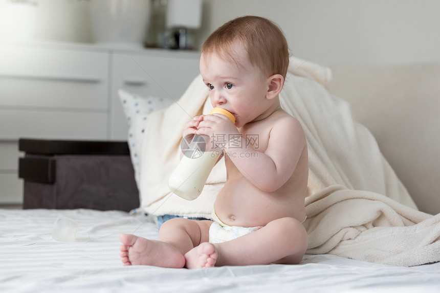 9个月大婴儿男孩坐在床上喝牛奶图片