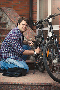 青年男子在家庭门廊修自行车背景图片