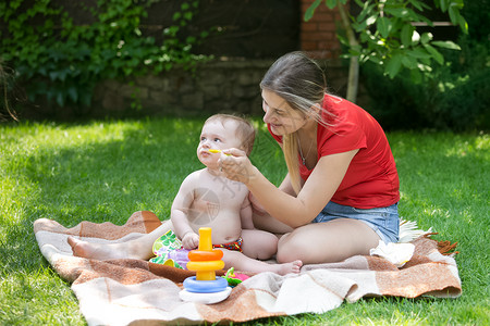 年轻母亲在公园的草地上喂小男孩图片