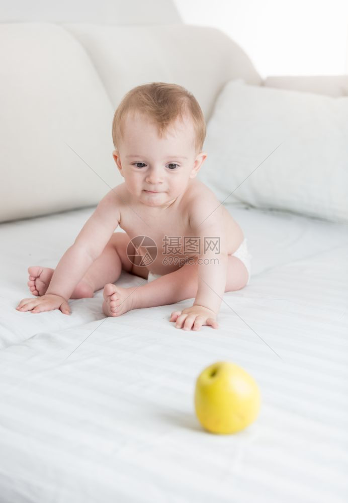10个月大的婴儿男孩在床上玩黄苹果图片