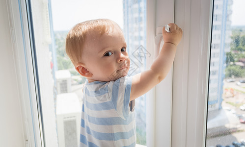 婴儿男孩拉着窗把手图片