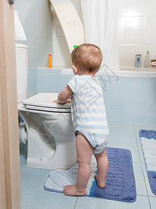 幼儿可爱男孩站在浴室和马桶上玩耍高清图片