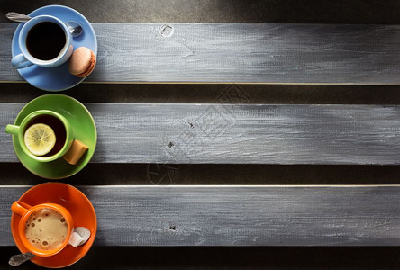 木板背景的橘绿蓝茶杯图片