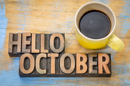 hello十月Hello10月贺卡旧式纸质印刷木制板用一杯咖啡抵挡有谷物的木柴背景