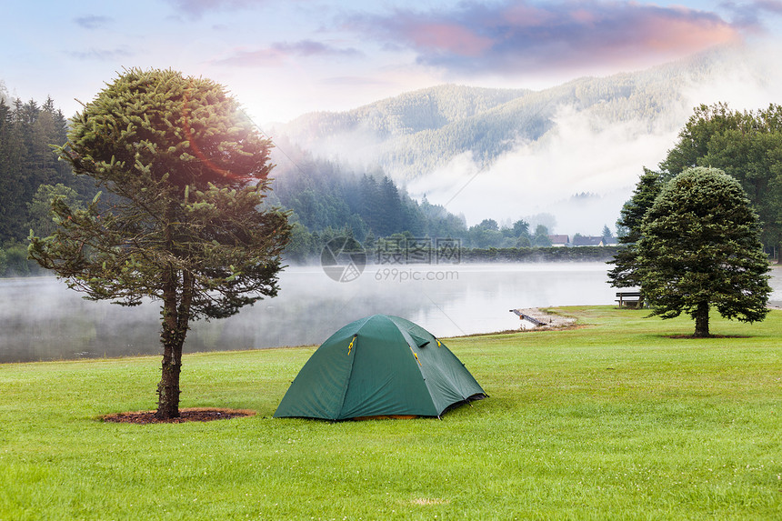 在山坡湖附近露营在绿草坪上安设帐篷图片