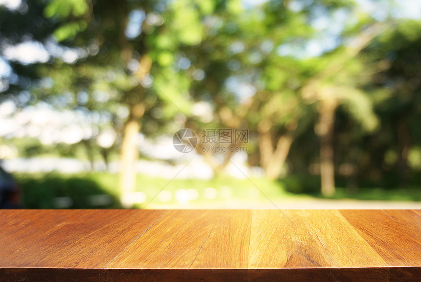 在户外花园灯光的抽象模糊背景前的木制桌子可以用于显示或装配产品图片
