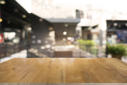 在咖啡馆和店内部的抽象模糊背景面前的空黑木桌可用于显示或调制产品背景图片
