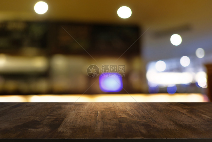 在咖啡馆和店内部的抽象模糊背景面前的空黑木桌可用于显示或调制产品图片