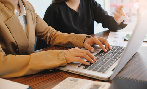 临时工女商人在网上用笔记本电脑工作手放在键盘上背景图片