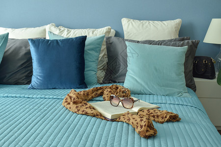 用枕头在蓝色床上用枕头贴着的蓝色床铺上有刀疤书和墨镜图片